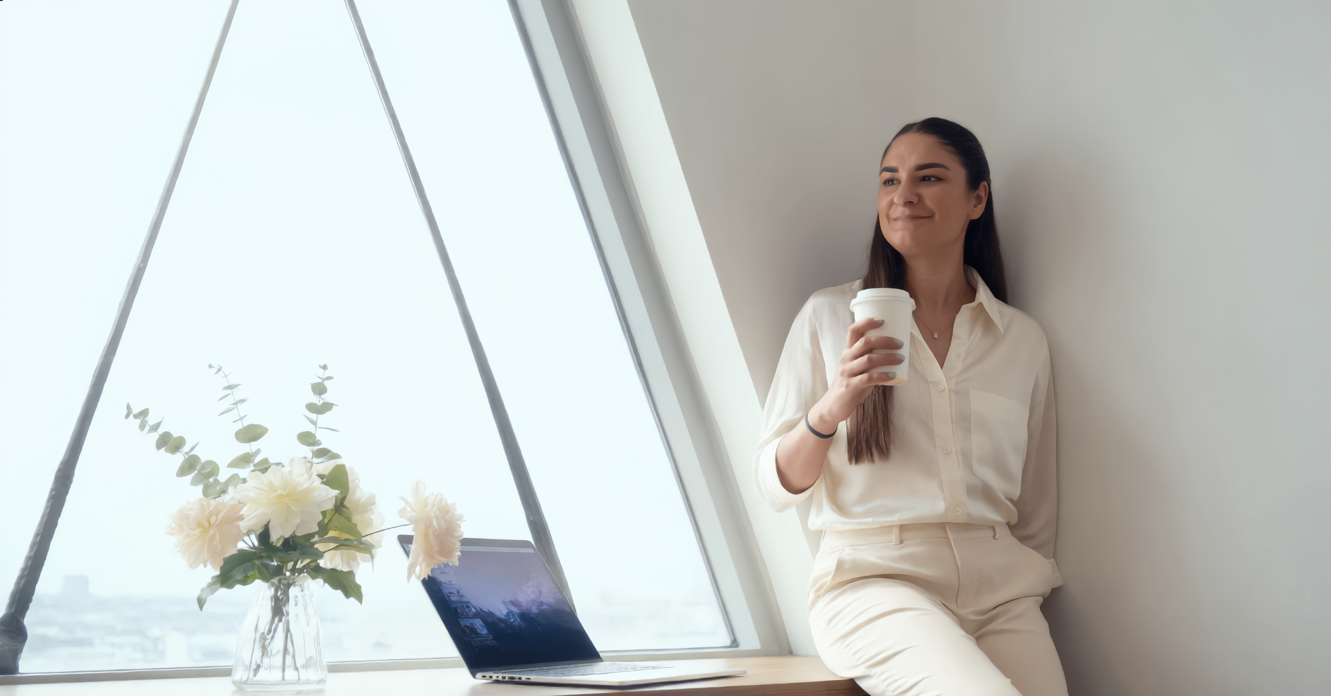Elica enjoying coffee by a window with a laptop